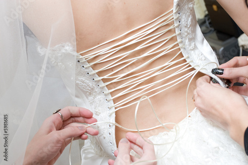 girls lace up a wedding dress of the bride photo