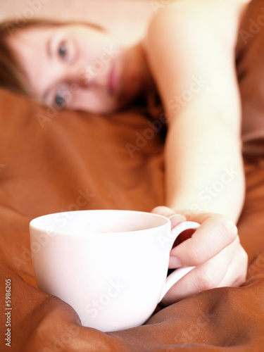 Young woman relaxing in the bedroom with coffee