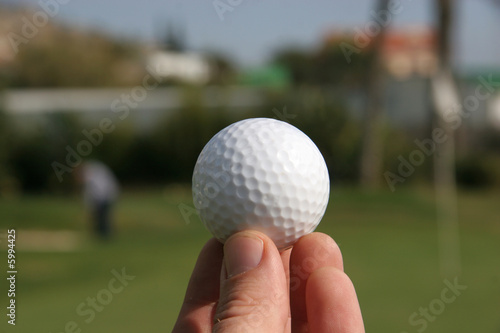 A golf ball in the hand of a golfer