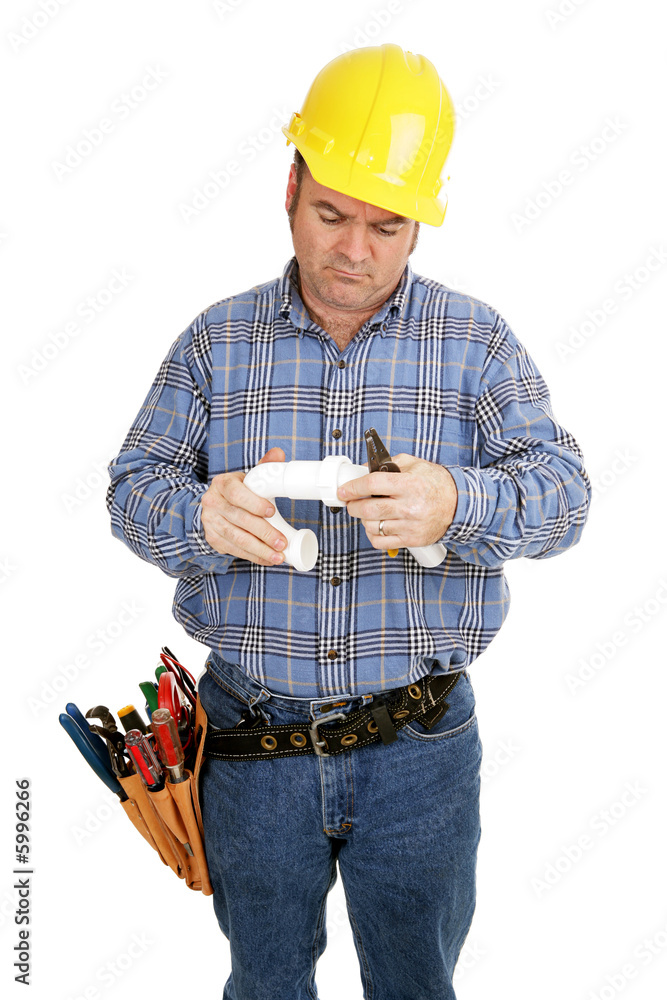 Electrician having trouble assembling plumbing pipe. Isolated Electrician having trouble assembling plumbing pipe. Isolated