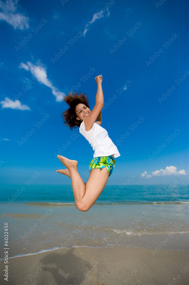 young beautiful girl jumping happily at the beach