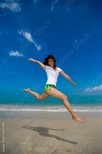 young beautiful girl jumping happily at the beach