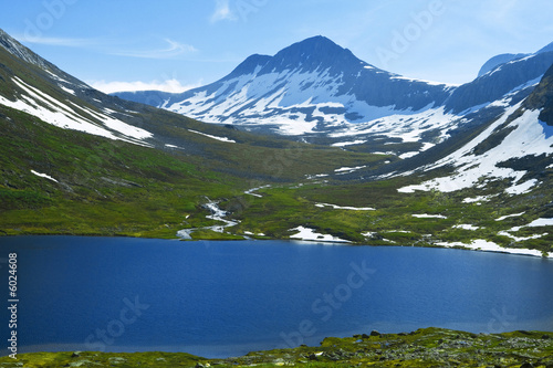 Blue lake in sumer time is around snow mountains
