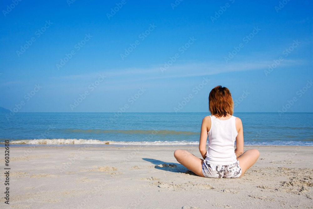 woman meditate by the beach facing the sea with blue sky