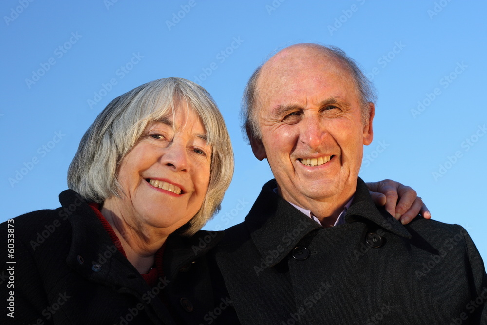 Senior couple embracing and smiling on a blue background. Senior couple embracing and smiling on a blue background.