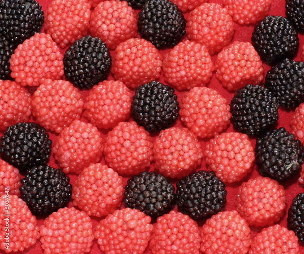 Sweets in the form of berries of a raspberry on a red background Sweets in the form of berries of a raspberry on a red background