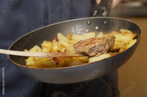 big cutlet on the woody handle and fried potatoes on pan
