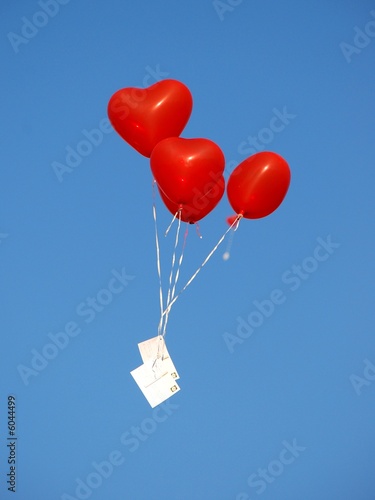 Rote herzförmige Luftballons mit Postkarte, blauer Himmel