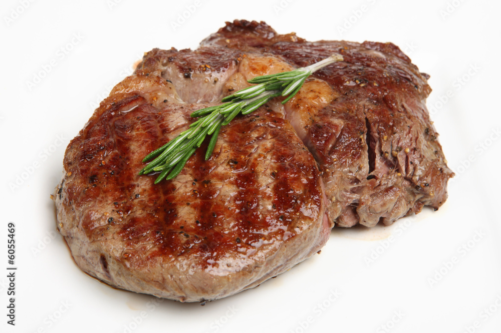 Rib-eye steak resting on a white plate Rib-eye steak resting on a white plate