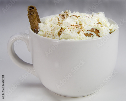 a steaming hot cup of cocoa with cinnamin sticks