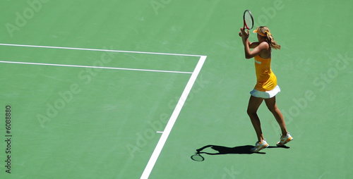 a girl in tennis action.  Yellow dress and green tennis field © kris@Positief