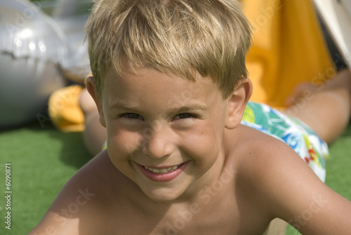 a happy five year old boy next to the swimming pool