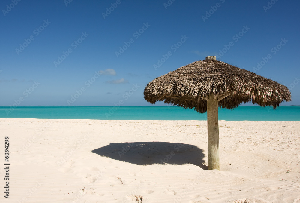 lone thatched sunshade on deserted tropical beach
