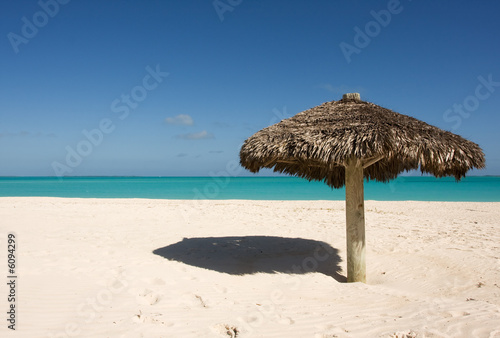 lone thatched sunshade on deserted tropical beach