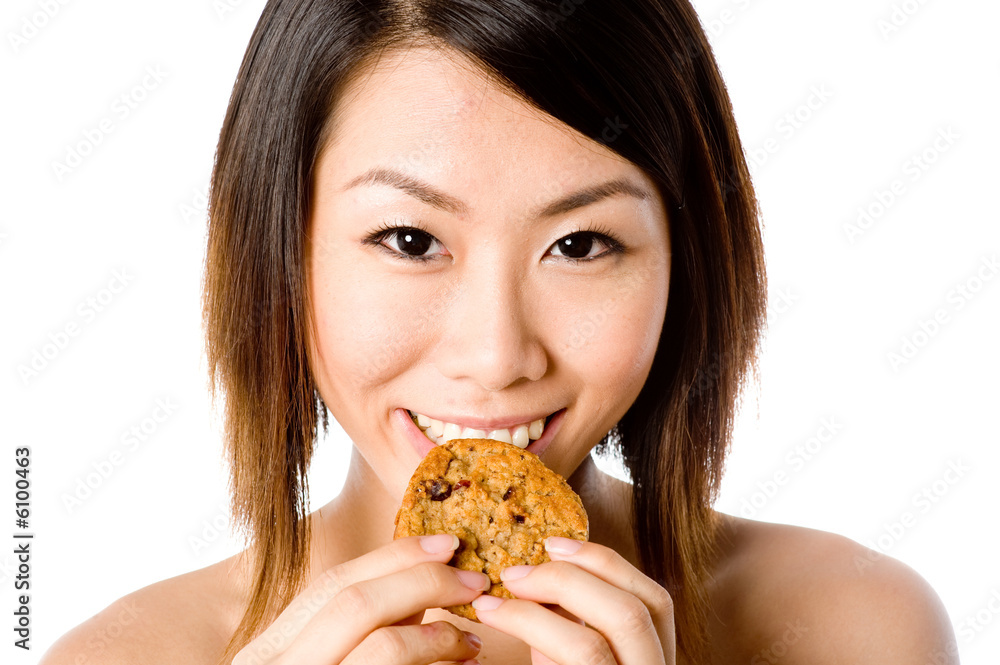 A pretty Asian woman eating a cookie A pretty Asian woman eating a cookie