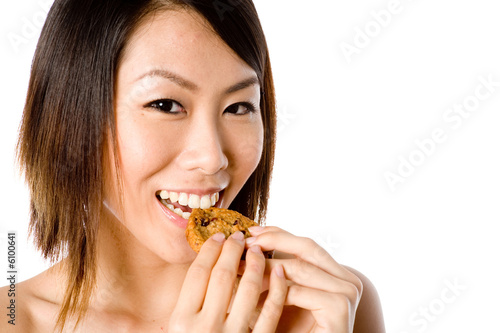 A pretty Asian woman eating a cookie