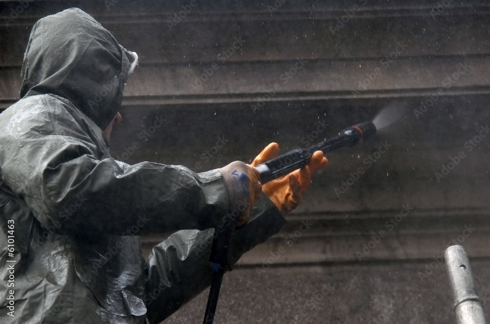 Worker washing and cleaning building facade Worker washing and cleaning building facade