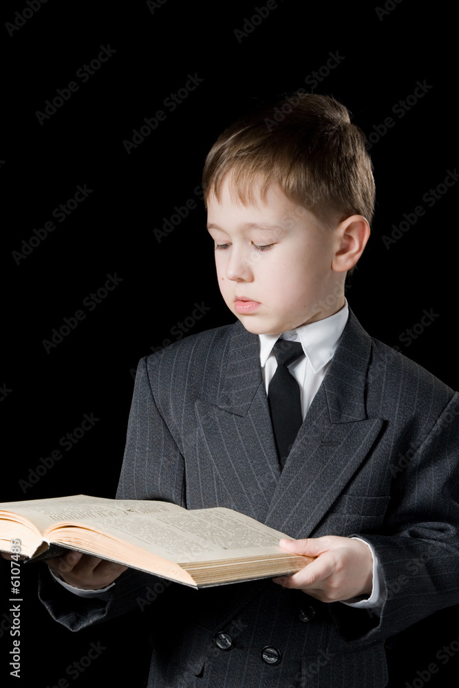 The boy reads the book. A black background.