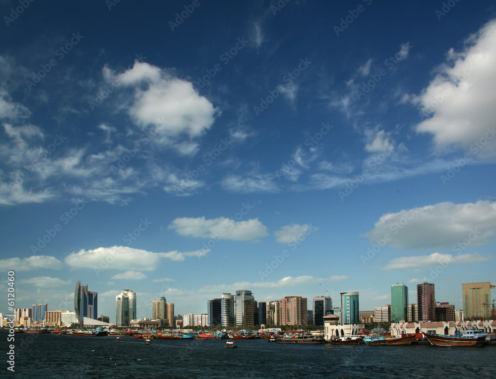 Fototapeta premium Dubai skyline with river, blue sky and white clouds