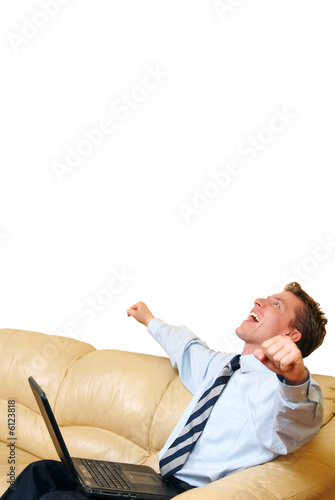 Young businessman with laptop on his lap enjoying a success