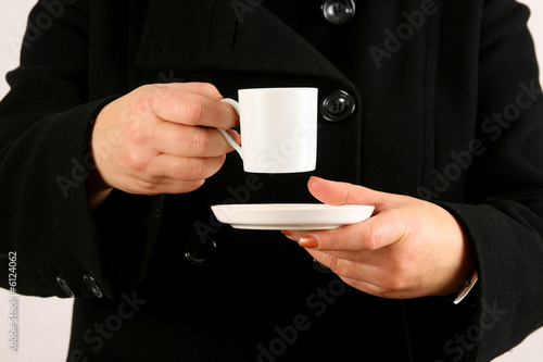 A woman holds a cup filled with black coffee or tea