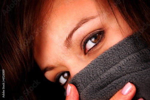 A woman's face with a sweater pulled up to her eyes.