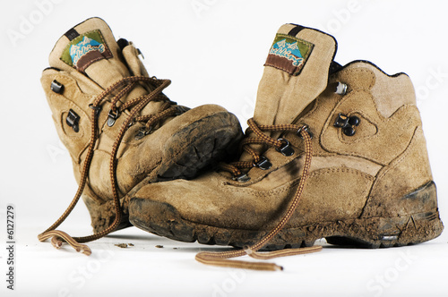 pair of trekking boots with mud on them on white background