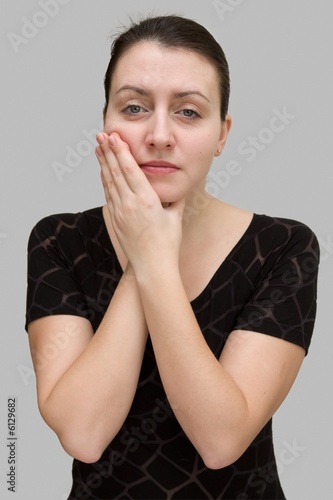 Toothache. Beautiful woman on a grey background. photo