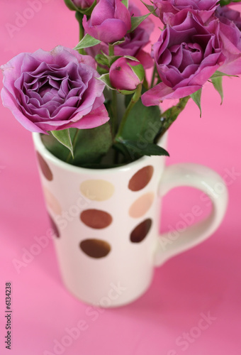 A bouquet of pink roses in a coffee mug