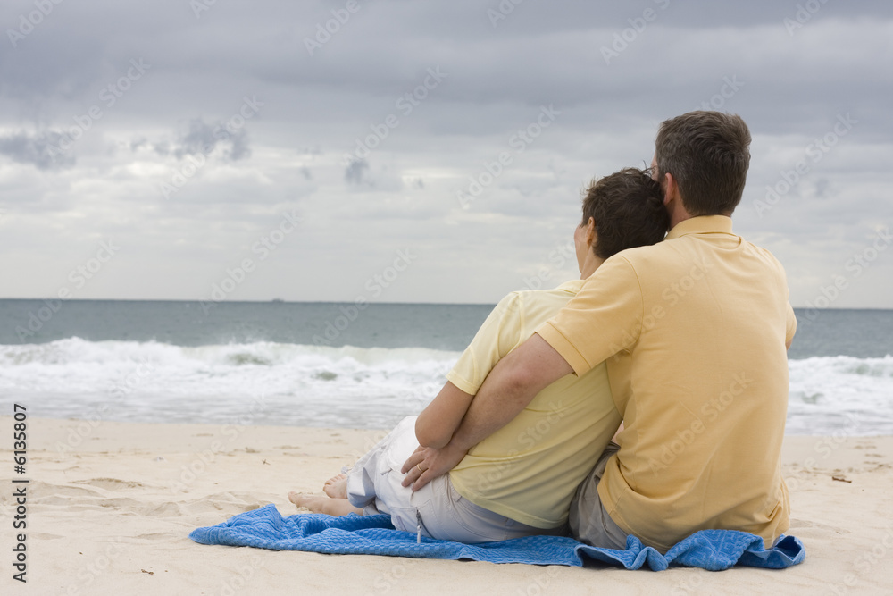 Sitzendes Paar Arm in Arm am Strand Sitzendes Paar Arm in Arm am Strand