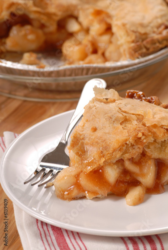 A slice of a deep dish apple pie with a flaky crust