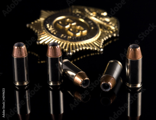 40 caliber bullets with gold badge on a black background