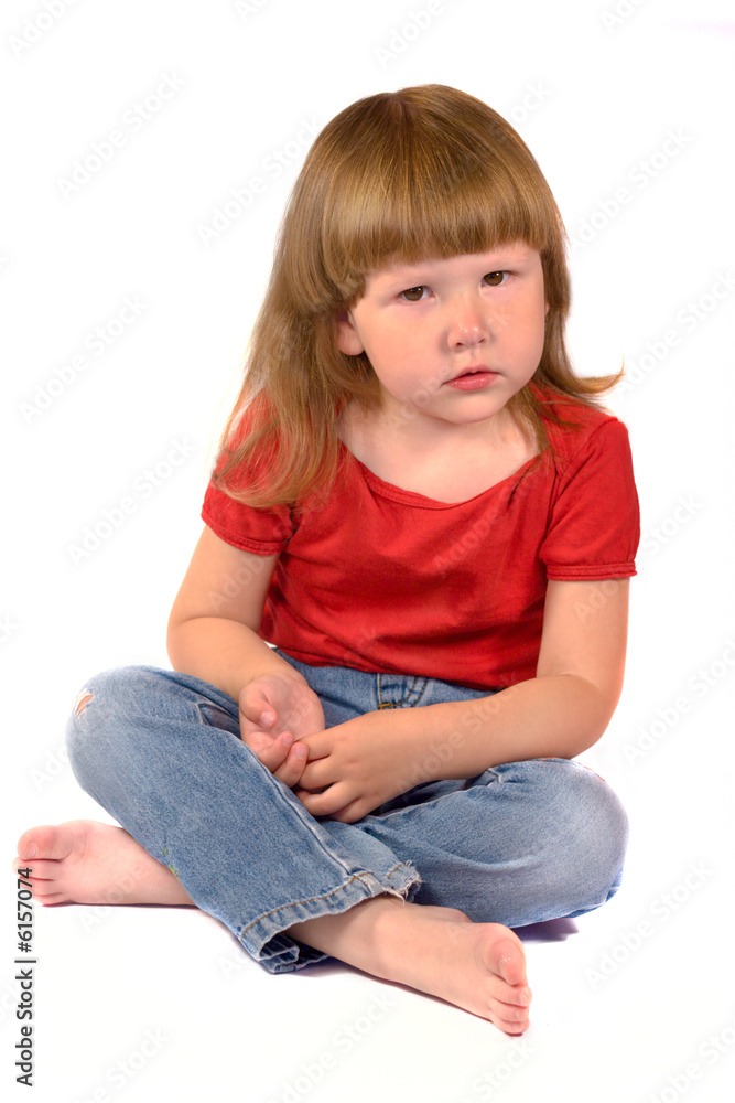 Serious kid sitting on the floor isolated on white Serious kid sitting on the floor isolated on white