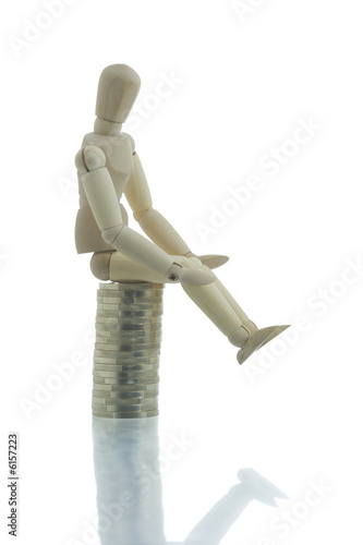 Manikin sitting on top of coins pile doing nothing