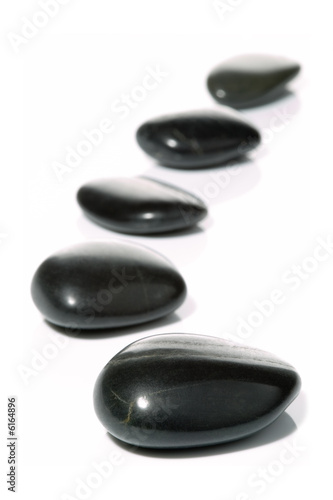 Five black pebbles in a gentle curve on a white surface 