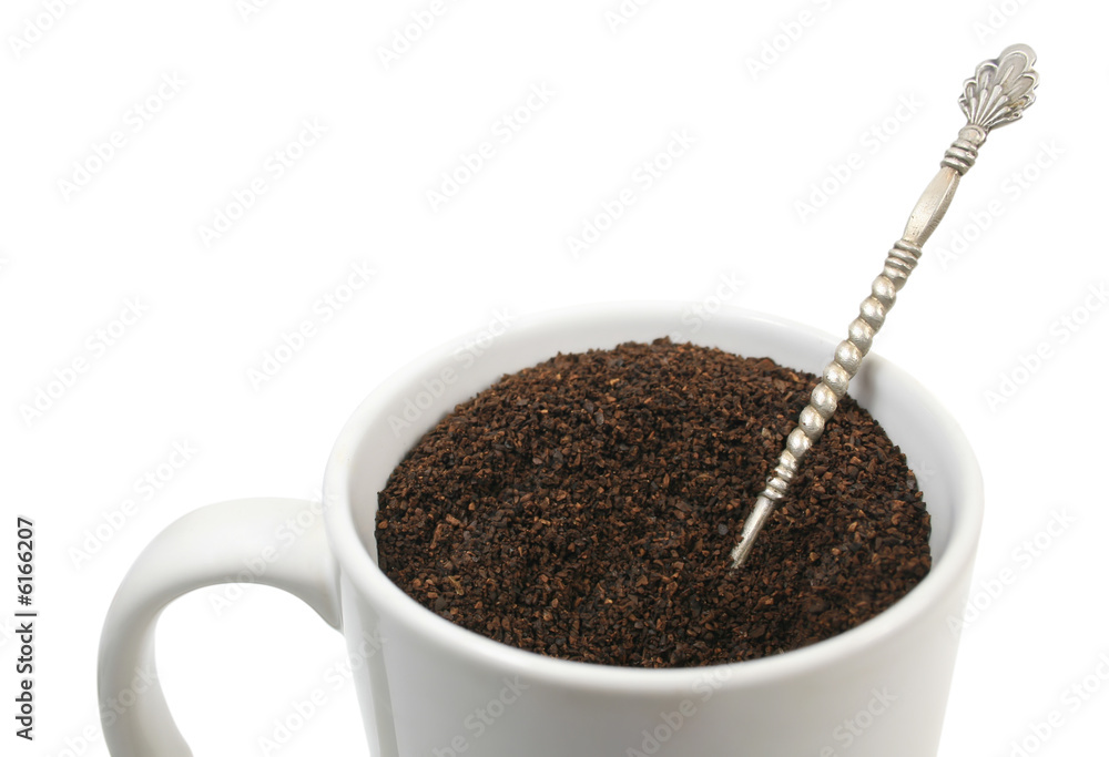 View of a white cup of ground coffee over white View of a white cup of ground coffee over white