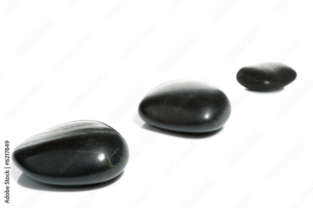 High key shot of three black pebbles on a white surface. High key shot of three black pebbles on a white surface.