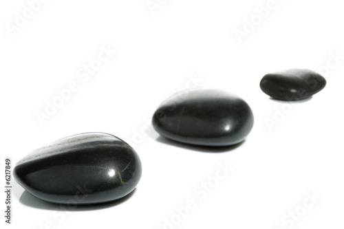 High key shot of three black pebbles on a white surface.