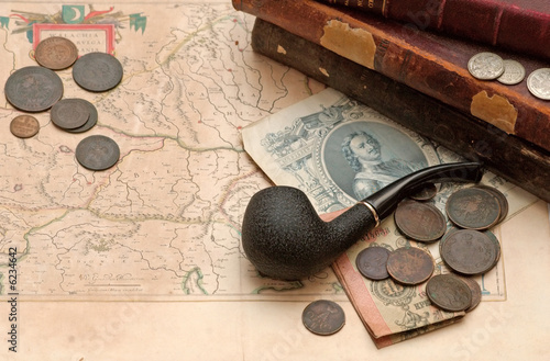 Old russian imperial books smoking pipe and coins over the map