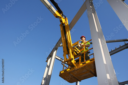 Tableau sur toile Construction worker operating cherry picker
