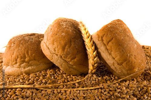 Three Wholemeal Rolls with Ear of Wheat on Bed of Wheat photo