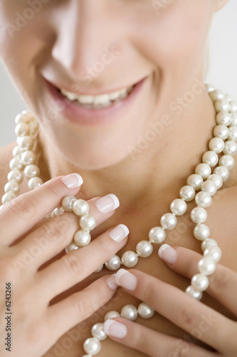 woman playing with her pearl necklace