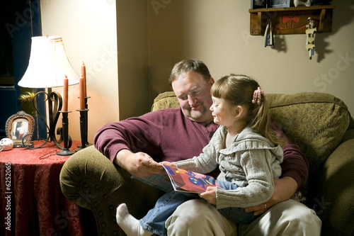 a little girl on grandpa's lap being read to.