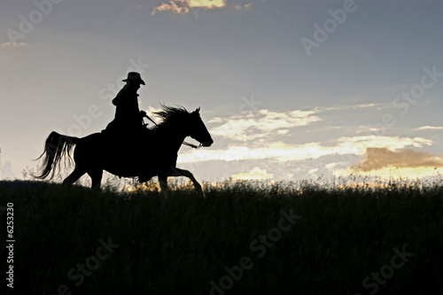 Cowboy riding acroos a Montana ridge at first light