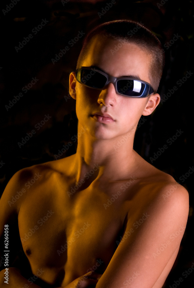 Shirtless teen boy in sunglasses looking tough. Stock Photo