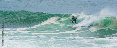 surfer surfs face of large powerful wave on the ocean 