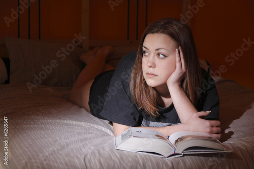 A girl with a book in the bedroom.