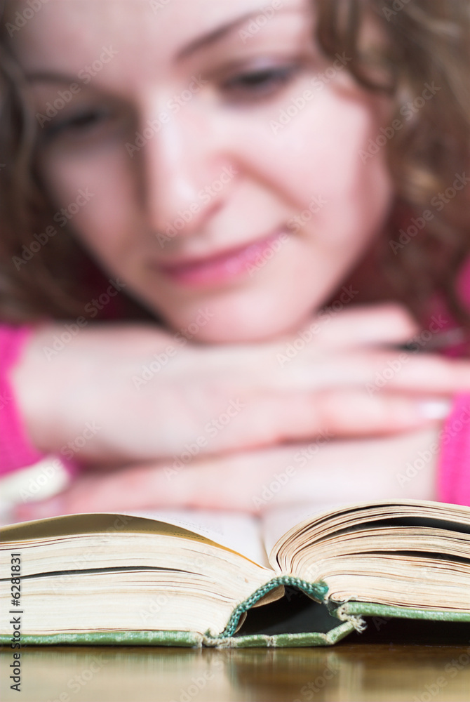 Pretty female is reading book. Primary focus is on book. Pretty female is reading book. Primary focus is on book.