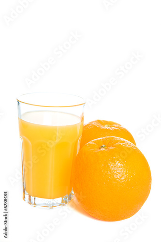 Two oranges and a glass of orange juice