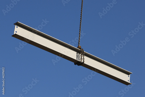 Steel girder swinging from a crane on a construction site photo